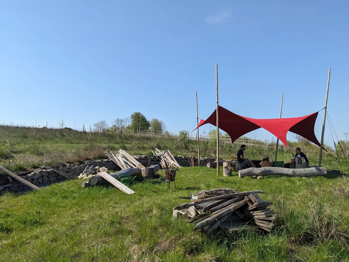 Das Bild zeigt die Lagebesprechung am Vielfaltwald unter dem knallroten Sonnensegel