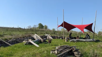 Das Bild zeigt die Lagebesprechung am Vielfaltwald unter dem knallroten Sonnensegel